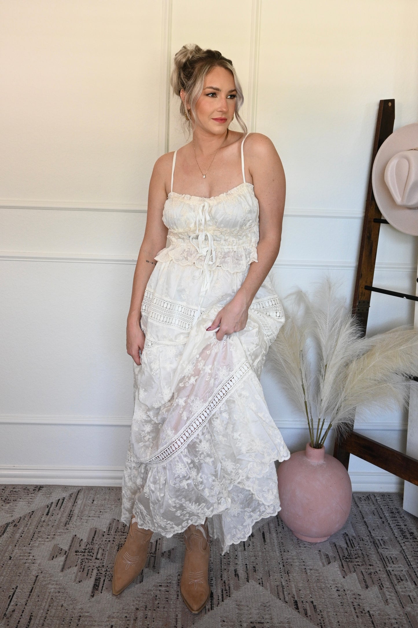 Woman in a ivory lace tank top and skirt set standing indoors with decorative elements.