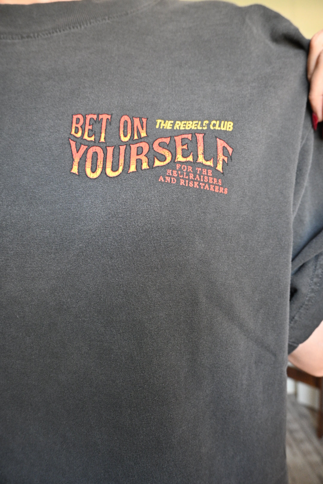 Black graphic tee with 'Bet On Yourself' text on a person wearing it.