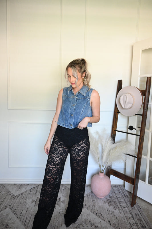 Woman wearing a denim vest and black lace pants standing on a decorative rug