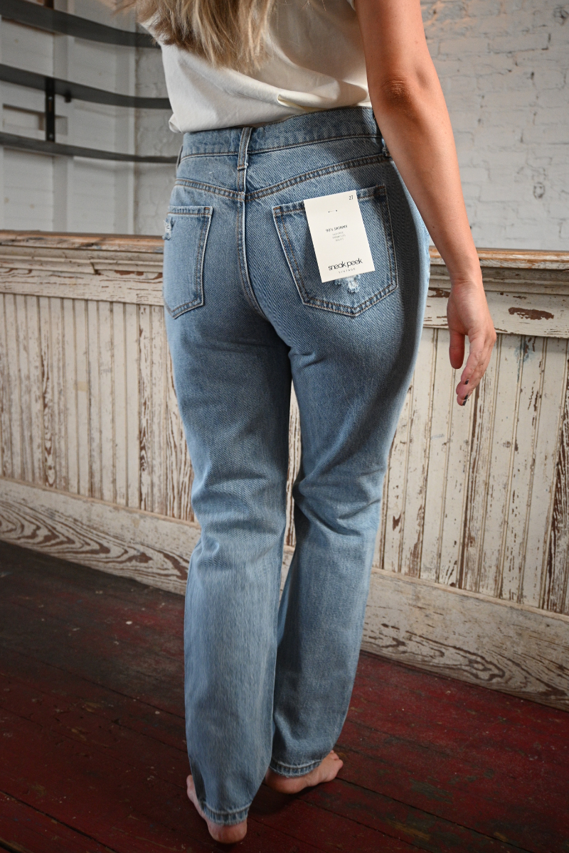 Back view of a barefoot woman wearing high rise light was skinny jeans.