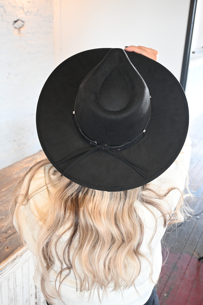 Back view of a woman wearing a black strap fedora hat.