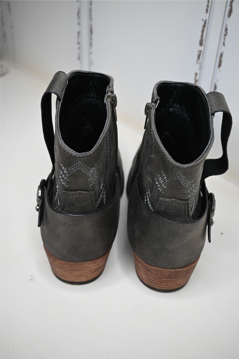 The Pierre Dumas buckle ankle boots are displayed on a white bench with the back of the boots facing towards the camera.