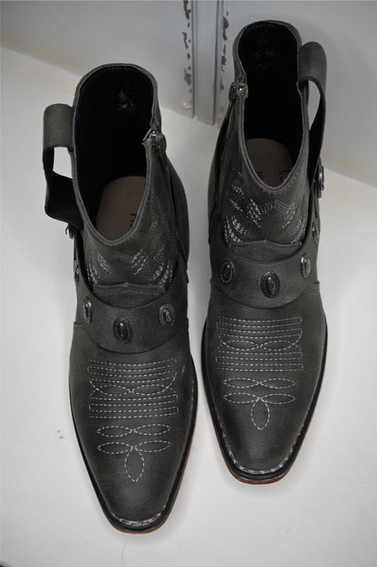 The Pierre Dumas buckle ankle boots are displayed on a white bench facing towards the camera.