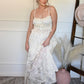 Woman in a ivory lace tank top and skirt set standing indoors with decorative elements.