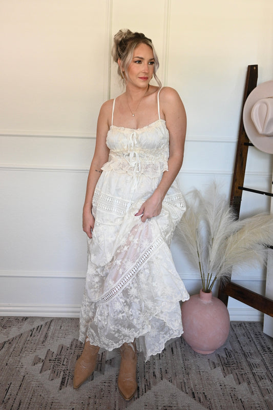 Woman in a ivory lace tank top and skirt set standing indoors with decorative elements.