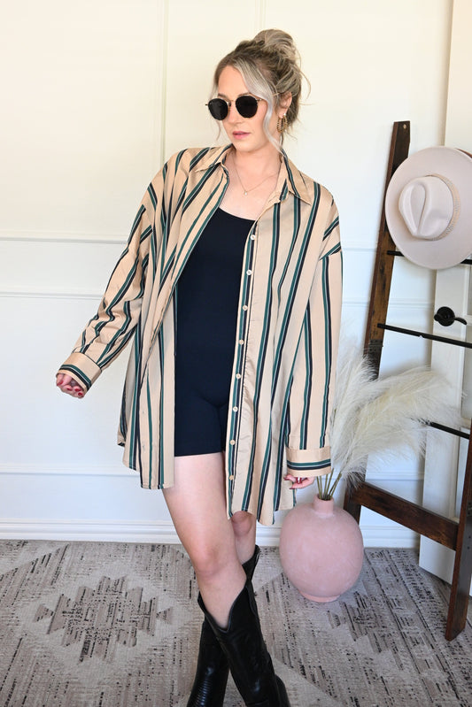 Woman in a striped shirt/dress standing next to a a decorative ladder.