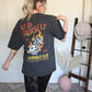 Person wearing a black t-shirt with graphic design and text, standing indoors.