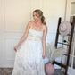 Woman holding one side of the top and lace skirt set in a room with a wooden floor and white walls.