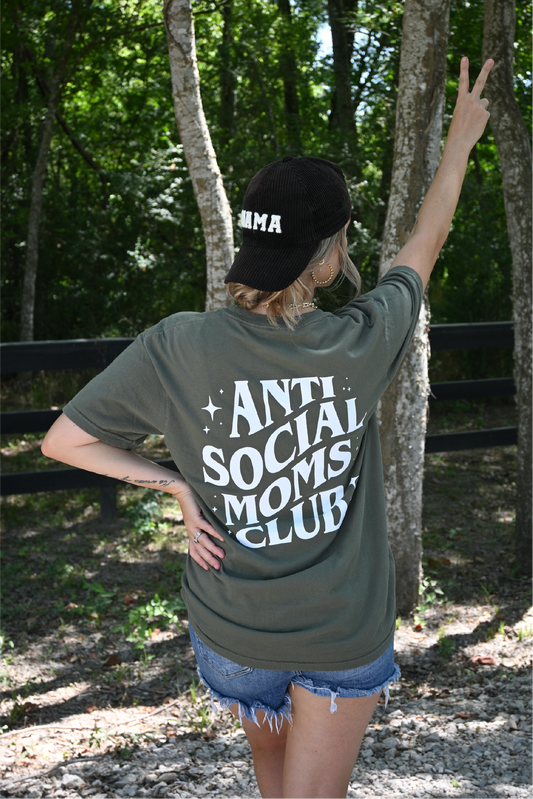 Model is showing the back of the sage colored graphic tee with "Anti Social Moms Club" paired with the Corduroy black "Mama" hat.