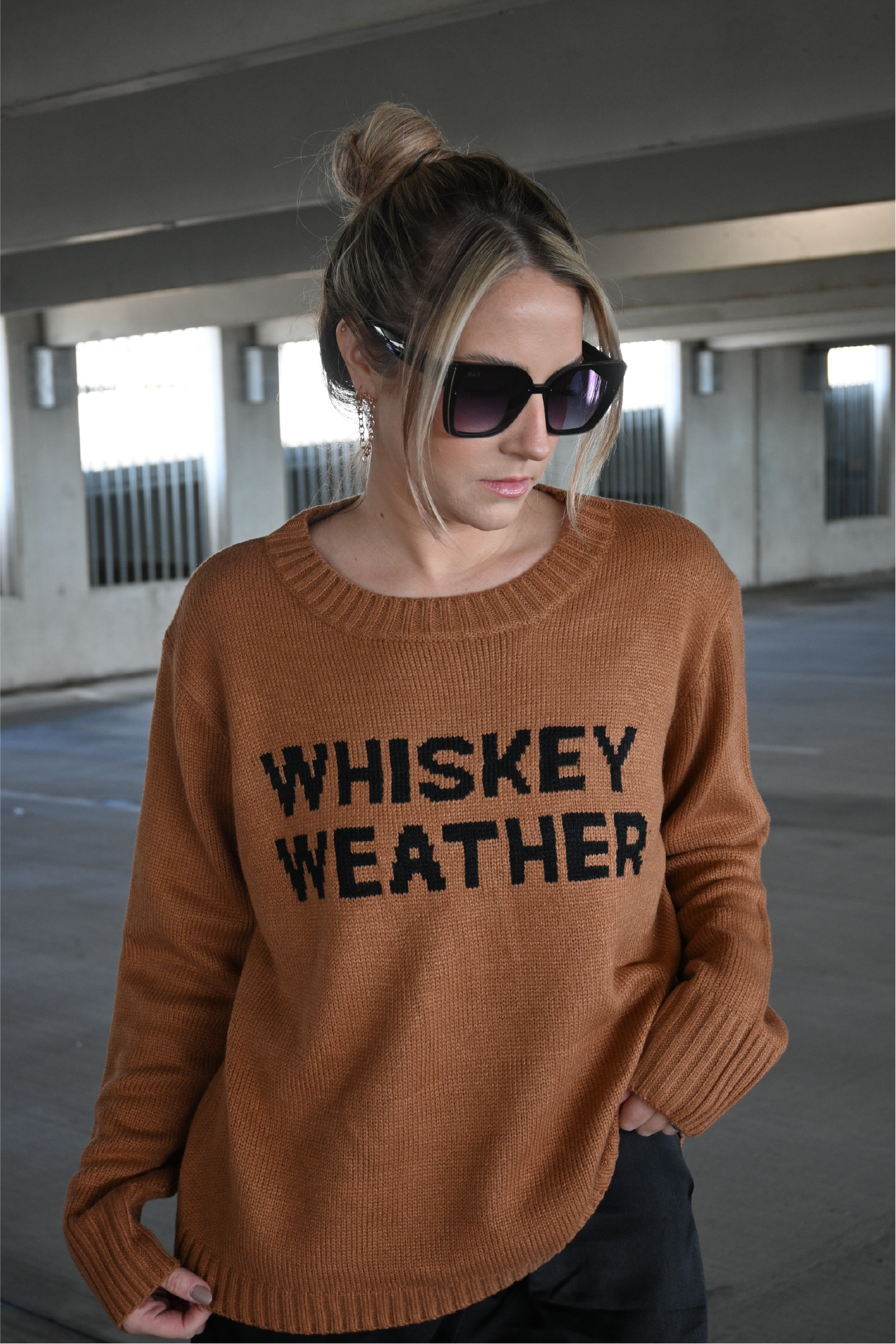 Up close image of the brown crewneck sweater with the words "Whiskey Weather" in black on the front. 