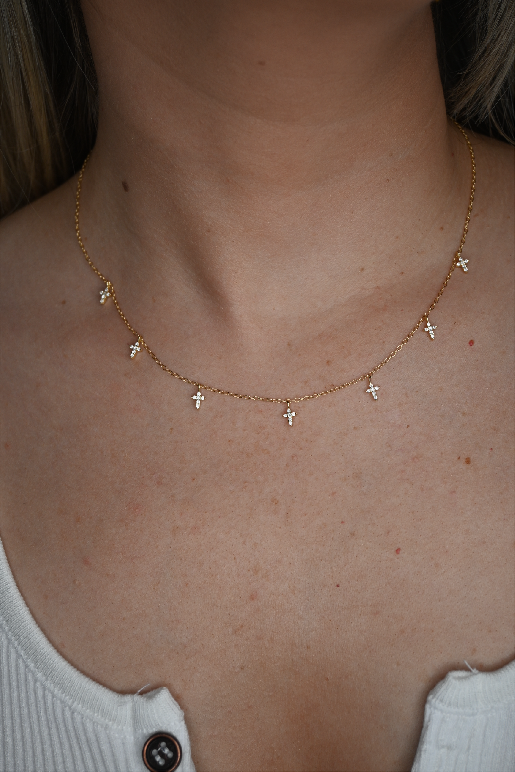 A close up shot of the seven cross necklace around a woman's neck.