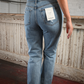Back view of a barefoot woman wearing high rise light was skinny jeans.