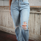 Front view of woman wearing high rise light wash skinny jeans with tears on both knees.