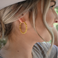 A close up of a woman looking off wearing the bead hoop earrings.