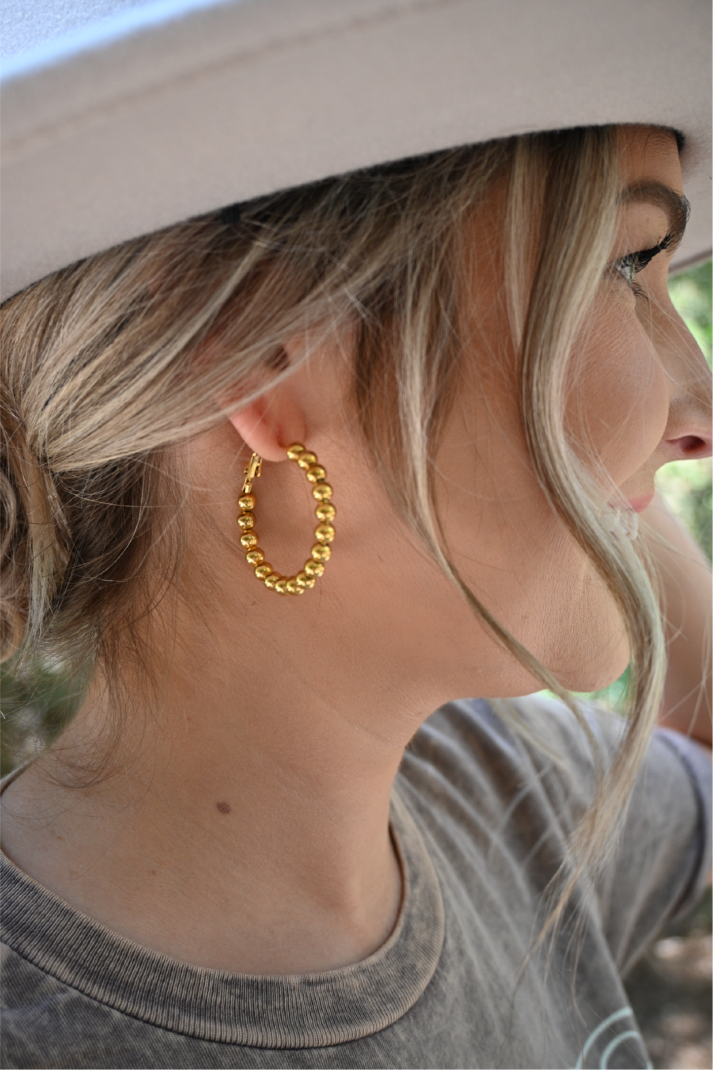 A close up of a woman looking off wearing the bead hoop earrings.