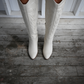 Womans legs wearing ivory colored western knee high boots.