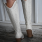 Back view of a woman wearing ivory colored knee high boots.