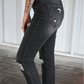 The side of dark grey distressed skinny jeans on a woman.