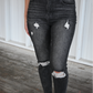 The front of dark grey distressed skinny jeans on a woman.
