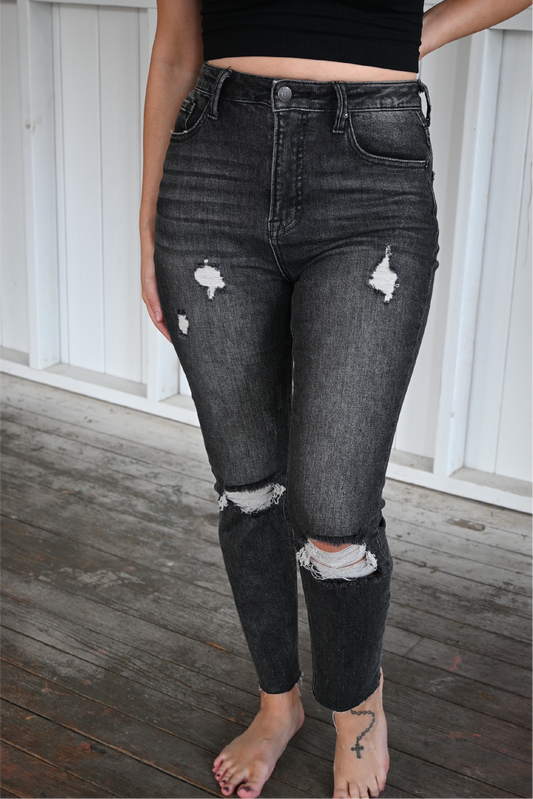 The front of dark grey distressed skinny jeans on a woman.