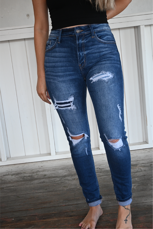 A close up shot of the front of the high rise ankle skinny kancan jeans. medium wash, distressed with button closure and cuffed at the bottom.