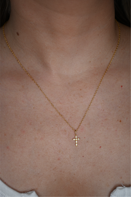 A close up shot of the vintage cross necklace on a woman's neck.