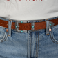 A close up view of a woman wearing a vintage turquoise stone studded belt.