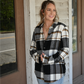 Model is smiling looking away from the camera holding the black brown plaid button down together paired with the 90's skinny high rise jeans and the gold chain neckalce and gold coin necklace.