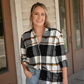 Model is smiling looking at the camera with one hand in her pocket and the other hand by her side. She is wearing the black brown plaid button down with one side tucked in the 90's skinny high rise jeans. She is also wearing the gold chain necklace paired with the gold coin necklace.