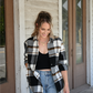 Model is looking down smiling with one hand in her pocket and the other hand by her side. She is wearing the black brown plaid button down open with the black ribbed cropped cami and the 90's skinny high rise jeans. She is also wearing the gold chain necklace paired with the gold coin necklace.