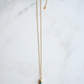 The turquoise spike gold necklace is laying on a white marble tile.